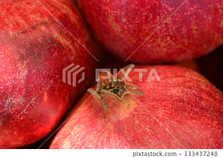 Vibrant pomegranates glistening under soft light showcase their tempting allure in a rustic setting 133437248