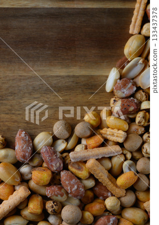 Colorful assortment of mixed nuts and snacks displayed on a wooden platter for an inviting party atmosphere 133437378