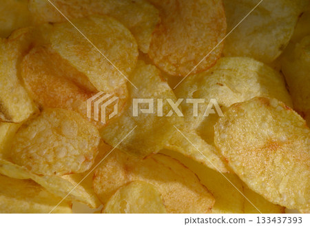 Crispy golden potato chips piled high, creating a tempting snack experience perfect for any occasion Crispy golden potato chips piled high, creating a tempting snack experience perfect for any occasion 133437393