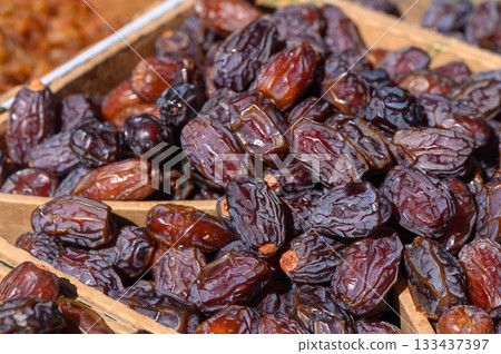 Sun-kissed dates showcased in a vibrant market during late afternoon hours, inviting passersby to indulge in their rich sweetness and health benefits 133437397