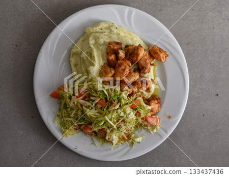 Deliciously prepared chicken pieces served with creamy mashed potatoes and fresh salad in a casual dining setting Deliciously prepared chicken pieces served with creamy mashed potatoes and fresh salad in a casual dining setting 133437436