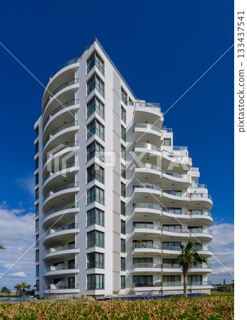 Modern architectural marvel rises against a brilliant blue sky in a coastal paradise Modern architectural marvel rises against a brilliant blue sky in a coastal paradise 133437541