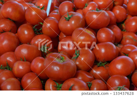 Vibrant red tomatoes piled high at a bustling market showcasing the harvest season's freshest produce 133437628