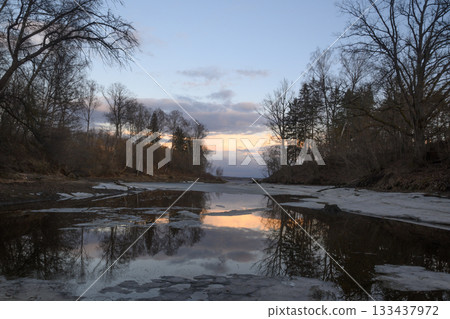 Serene twilight over a tranquil river reflecting the soft hues of dusk in early spring Serene twilight over a tranquil river reflecting the soft hues of dusk in early spring 133437972