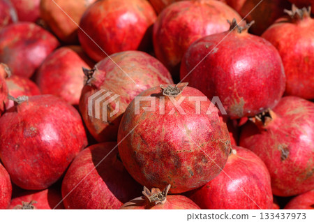 Vibrant pomegranates stacked together showcasing their rich color and freshness at a bustling market in autumn Vibrant pomegranates stacked together showcasing their rich color and freshness at a bustling market in autumn 133437973