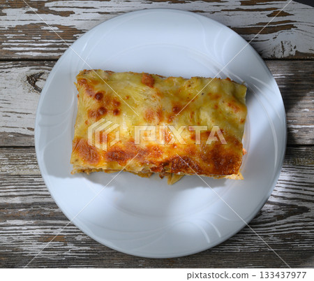 Deliciously baked lasagna with golden cheese, ready to be enjoyed at a cozy kitchen table during a weekend feast 133437977