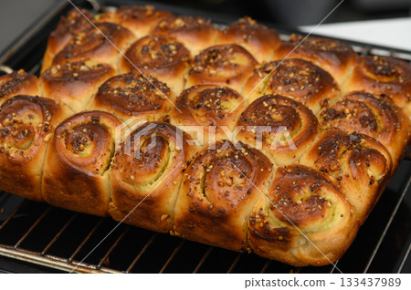 Deliciously baked bread rolls topped with spices fresh out of the oven, tempting aroma fills the air in a cozy kitchen Deliciously baked bread rolls topped with spices fresh out of the oven, tempting aroma fills the air in a cozy kitchen 133437989