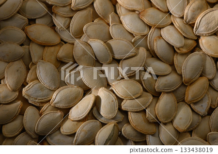 Countless pumpkin seeds glisten in the warm afternoon light, celebrating the harvest season with their earthy hues and intricate shapes Countless pumpkin seeds glisten in the warm afternoon light, celebrating the harvest season with their earthy hues and intricate shapes 133438019