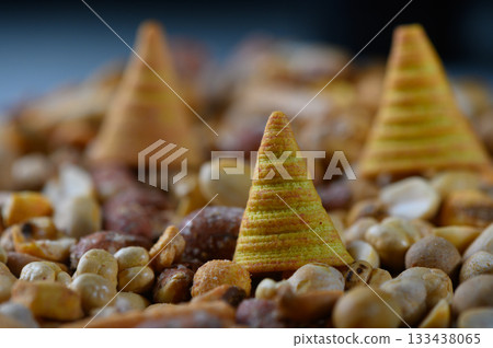 Colorful conical snacks amidst a vibrant assortment of mixed nuts creating an inviting snack display at a festive gathering 133438065