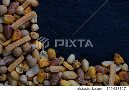 Colorful assortment of crunchy snacks arranged artistically on a dark surface creates an inviting atmosphere for casual gatherings Colorful assortment of crunchy snacks arranged artistically on a dark surface creates an inviting atmosphere for casual gatherings 133438117