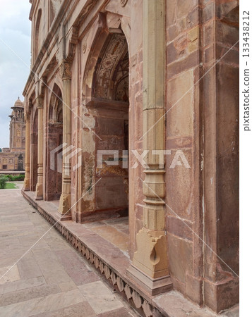 Side angle view of small red sandstone palace with ornate lattice stone arches, showing intricately carved archways, traditional Mughal architecture in India, historical heritage monument 133438212