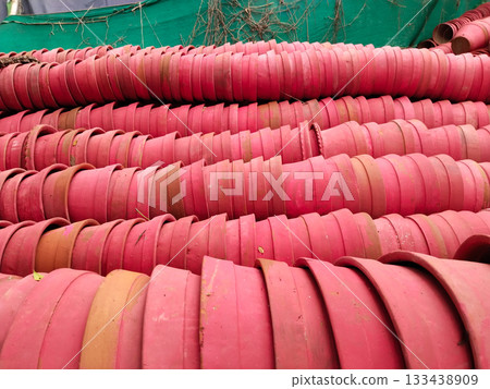 Rows of empty terracotta plant pots stacked in bulk, classic red clay planters prepared for gardening in outdoor storage area 133438909