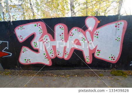 The old wall decorated with paint stains in the style of street art culture. Colorful background of full graffiti painting artwork with bright aerosol outlines on wall. Colored background texture The old wall decorated with paint stains in the style of street art culture. Colorful background of full graffiti painting artwork with bright aerosol outlines on wall. Colored background texture 133439826