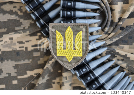 Ukrainian army symbol on machine gun belt lies on ukrainian pixeled military camouflage close up 133440347