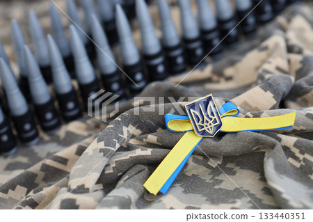 Ukrainian symbol and a machine gun belt on the camouflage uniform of a Ukrainian soldier. The Concept of war in Ukraine, patriotism and protecting your country from russian occupiers 133440351
