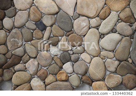 Yellow and brown round shaped pebble stone wall texture close up 133440362