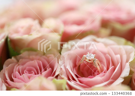 Gold diamond engagement ring in beautiful pink rose flower among big amount of roses in big bouquet close up with blurred background Gold diamond engagement ring in beautiful pink rose flower among big amount of roses in big bouquet close up with blurred background 133440368