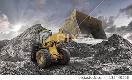 A loader works efficiently to shift large piles of dirt and debris at a busy construction site during late afternoon with dramatic clouds overhead A loader works efficiently to shift large piles of dirt and debris at a busy construction site during late afternoon with dramatic clouds overhead 133440906