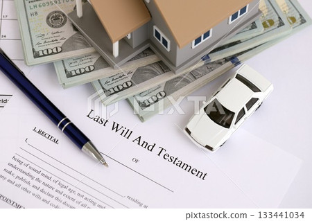 Generic toy house with US dollar bills, car and Last will and testament with pen on table close up Generic toy house with US dollar bills, car and Last will and testament with pen on table close up 133441034