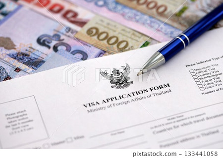 Visa application form to enter Thailand on table with pen and thai money bills close up 133441058
