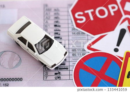 Driving school concept. Toy car and road signs on driver license close up 133441059