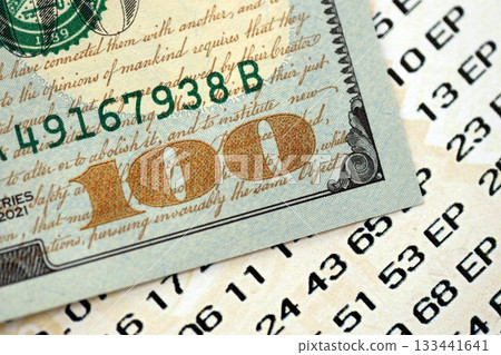 Lottery ticket and one hundred US dollar bill close up. Concept of gambling addiction and lottery 133441641