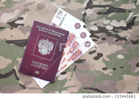 Russian passport with money on multicam camouflage fabric close up. Concept of russian army funds and invasion to Ukraine Russian passport with money on multicam camouflage fabric close up. Concept of russian army funds and invasion to Ukraine 133441661