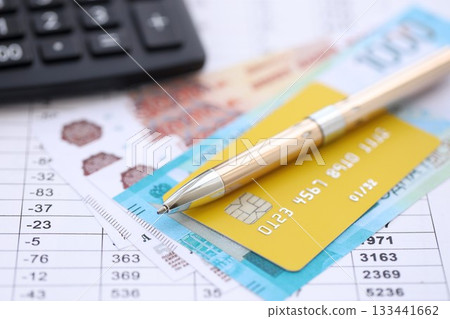Credit card and pen with russian ruble currency money bills banknotes on calculations document background. Business, financial operations and accounting in Russian Federation 133441662
