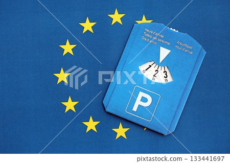 Parking disc for windshield on European Union flag. Limited time parking system in european countries. Concept of parking time count in busy parking lots 133441697