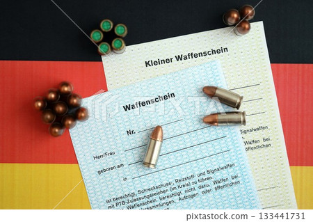 German firearms licenses and bullets on Germany flag close up. Gun permit for weapon carrying in Deutschland German firearms licenses and bullets on Germany flag close up. Gun permit for weapon carrying in Deutschland 133441731