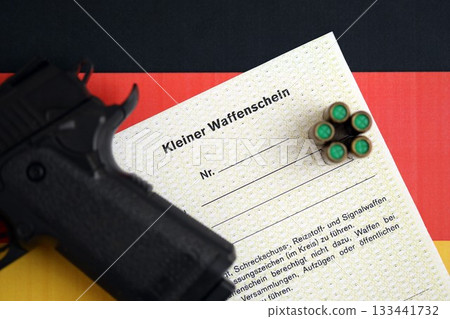German light firearms license and handgun with bullets on Germany flag close up. Gun permit for light weapon carrying in Deutschland 133441732