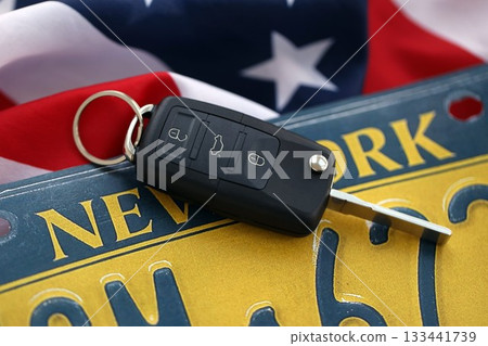 Remote control car keys on New York license plate on US flag. Concept of driving in New York. Reaching a driving permit 133441739