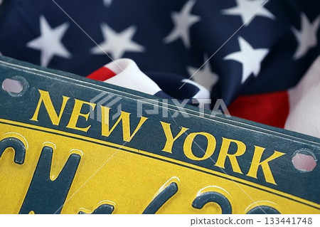 USA state of New York license plate on US flag. Concept of driving in New York. Reaching a driving permit USA state of New York license plate on US flag. Concept of driving in New York. Reaching a driving permit 133441748