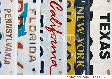 Old US car license plates with various state names close up. Concept of driving in United States. Reaching a car registration 133441765