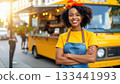 Happy entrepreneur smiling in front of her yellow street food truck. 133441993