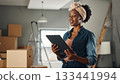 African american woman holding digital tablet in a room undergoing renovation. 133441994