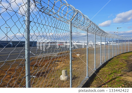 Razor barbed wire or concertina razor coil barrier security fence restricted security area in airport. Neural network ai generated art Razor barbed wire or concertina razor coil barrier security fence restricted security area in airport. Neural network ai generated art 133442422