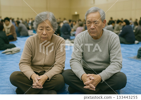 Elderly men and women sitting on a blue sheet in a gymnasium at an evacuation shelter_AI generated Elderly men and women sitting on a blue sheet in a gymnasium at an evacuation shelter_AI generated 133443255