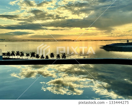 Sunset clouds and golden sky reflected on the water Sunset clouds and golden sky reflected on the water 133444275