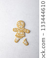 Gingerbread man with a broken leg (without leg) and with a surprised face. Traditional New Year and Christmas homemade cookies on a white background. Selective focus, close-up. 133444610