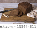 Rye Borodino (Borodinskiy) bread with a crispy crust on a wooden board, cut into slices. Homemade baking in rustic style. Selective focus, close-up. 133444611