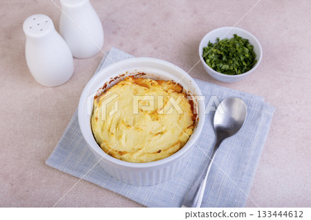 Shepherd's pie in a portioned white baking dish. Homemade traditional casserole (gratin) with minced meat and mashed potatoes. Selective focus, close-up. Shepherd's pie in a portioned white baking dish. Homemade traditional casserole (gratin) with minced meat and mashed potatoes. Selective focus, close-up. 133444612