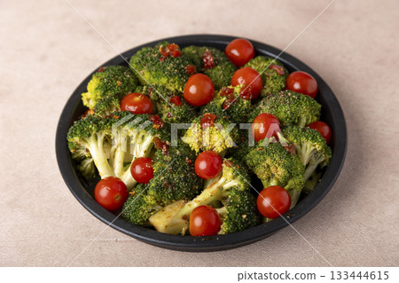 Broccoli cabbage marinated in spicy-sweet sauce and spices with cherry tomatoes. Preparing for baking. Healthy home cooking. Selective focus, close-up. Broccoli cabbage marinated in spicy-sweet sauce and spices with cherry tomatoes. Preparing for baking. Healthy home cooking. Selective focus, close-up. 133444615