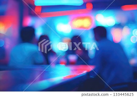 Defocused group socializing at bar with neon lights, vibrant colors, and relaxed atmosphere, creating lively nightlife scene with blurred people enjoying drinks and conversation 133445625