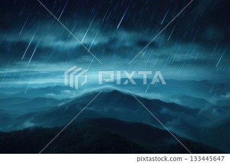 Rain falling over misty mountain landscape with blurred clouds, dramatic night sky, and defocused lightning storm, creating moody and atmospheric scene 133445647