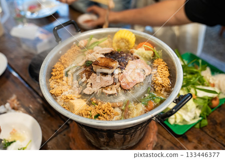 Sliced meat and vegetables cook in a metal grill pot filled with broth and steam, while the center grill browns the meat. Sliced meat and vegetables cook in a metal grill pot filled with broth and steam, while the center grill browns the meat. 133446377