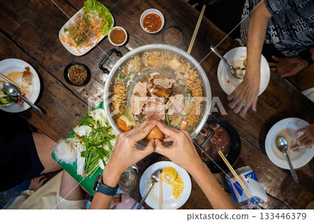Sliced meat and vegetables cook in a metal grill pot filled with broth and steam, while the center grill browns the meat. Sliced meat and vegetables cook in a metal grill pot filled with broth and steam, while the center grill browns the meat. 133446379