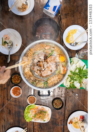 Sliced meat and vegetables cook in a metal grill pot filled with broth and steam, while the center grill browns the meat. Sliced meat and vegetables cook in a metal grill pot filled with broth and steam, while the center grill browns the meat. 133446383