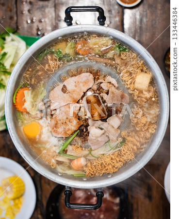 Sliced meat and vegetables cook in a metal grill pot filled with broth and steam, while the center grill browns the meat. Sliced meat and vegetables cook in a metal grill pot filled with broth and steam, while the center grill browns the meat. 133446384