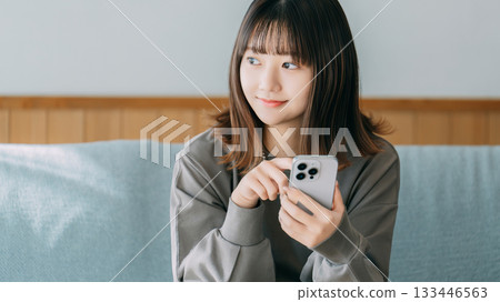 坐長沙發和使用智能手機的婦女 坐長沙發和使用智能手機的婦女 133446563